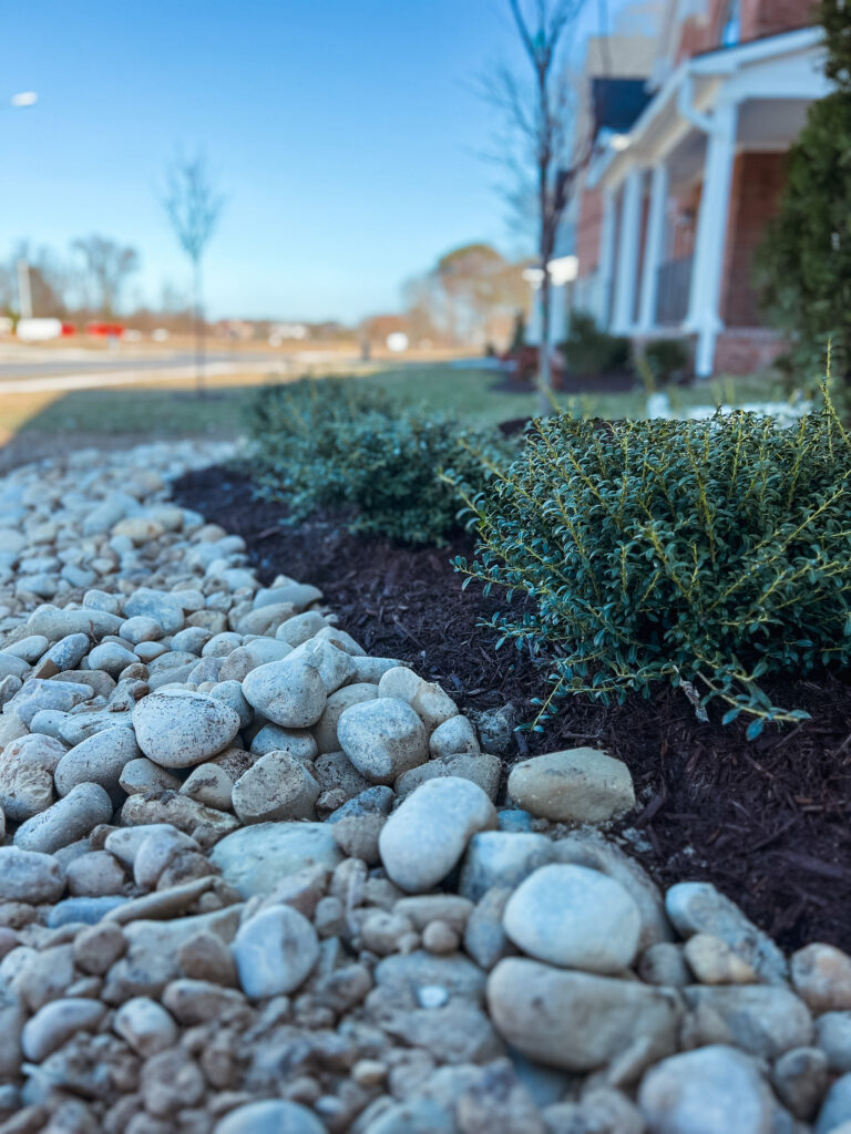 flower bed with river rock and shrubs