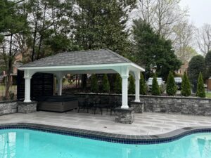 Pavilion with shingled roof and open lounge area beside a swimming pool in a Virginia backyard