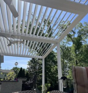 Sleek louvered pergola with white aluminum slats providing shade over a modern Virginia patio.