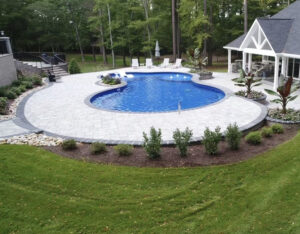 Top-down view of a modern backyard patio with pool, pool house, fire pit and lounge area in a Virginia home.
