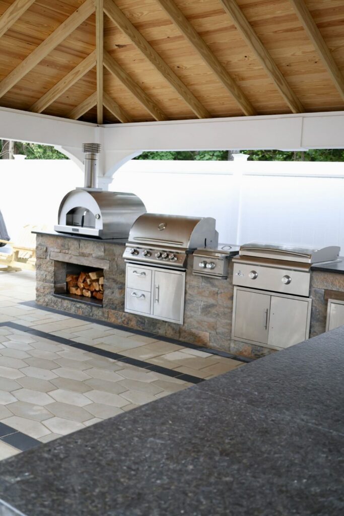 Custom outdoor kitchen with pizza oven, grill, and wood storage