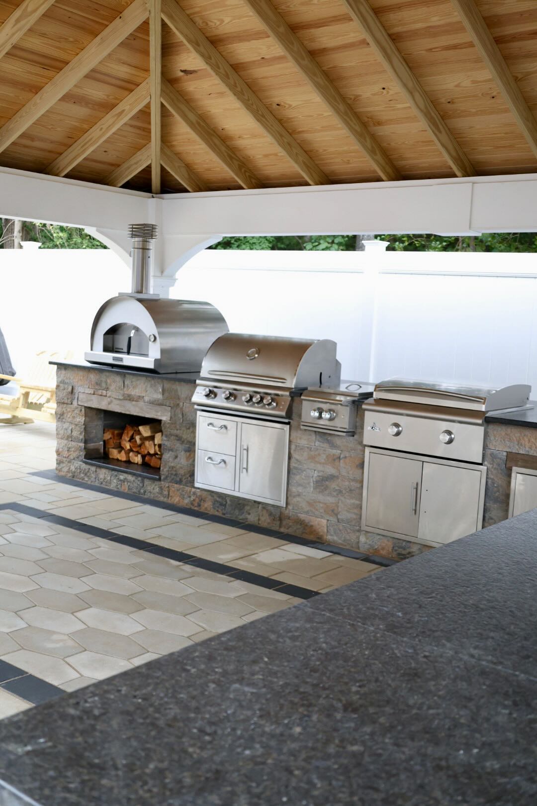 Custom outdoor kitchen with pizza oven, grill, and wood storage