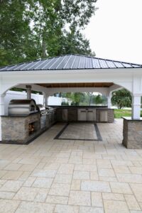 Covered outdoor kitchen with stone countertops and built-in grill