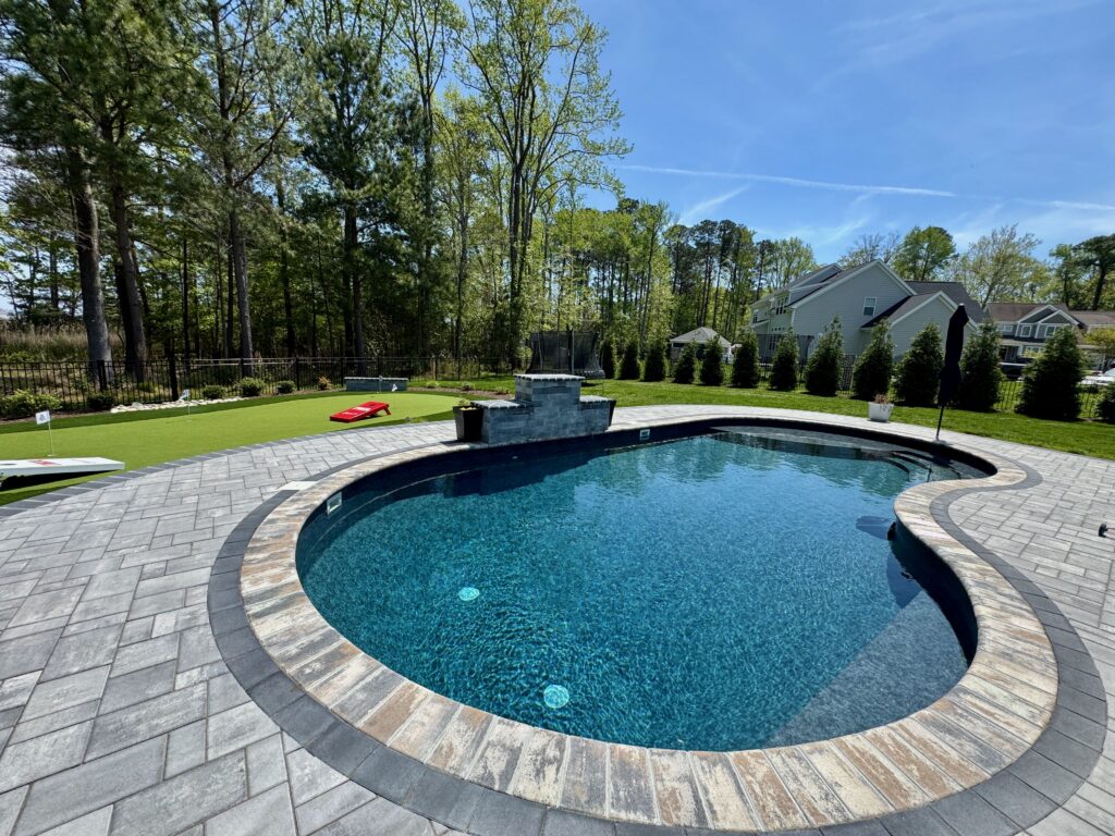 Kidney-shaped pool with multicolor paver coping and deck