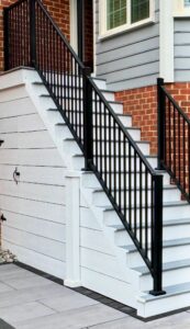 Modern exterior staircase built with composite steps and black aluminum railing leading to a brick and siding Virginia home.