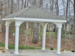 White vinyl pavilion in wooded backyard setting
